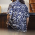 Person wearing a blue patterned shirt with black and white illustrations of muscular figures.